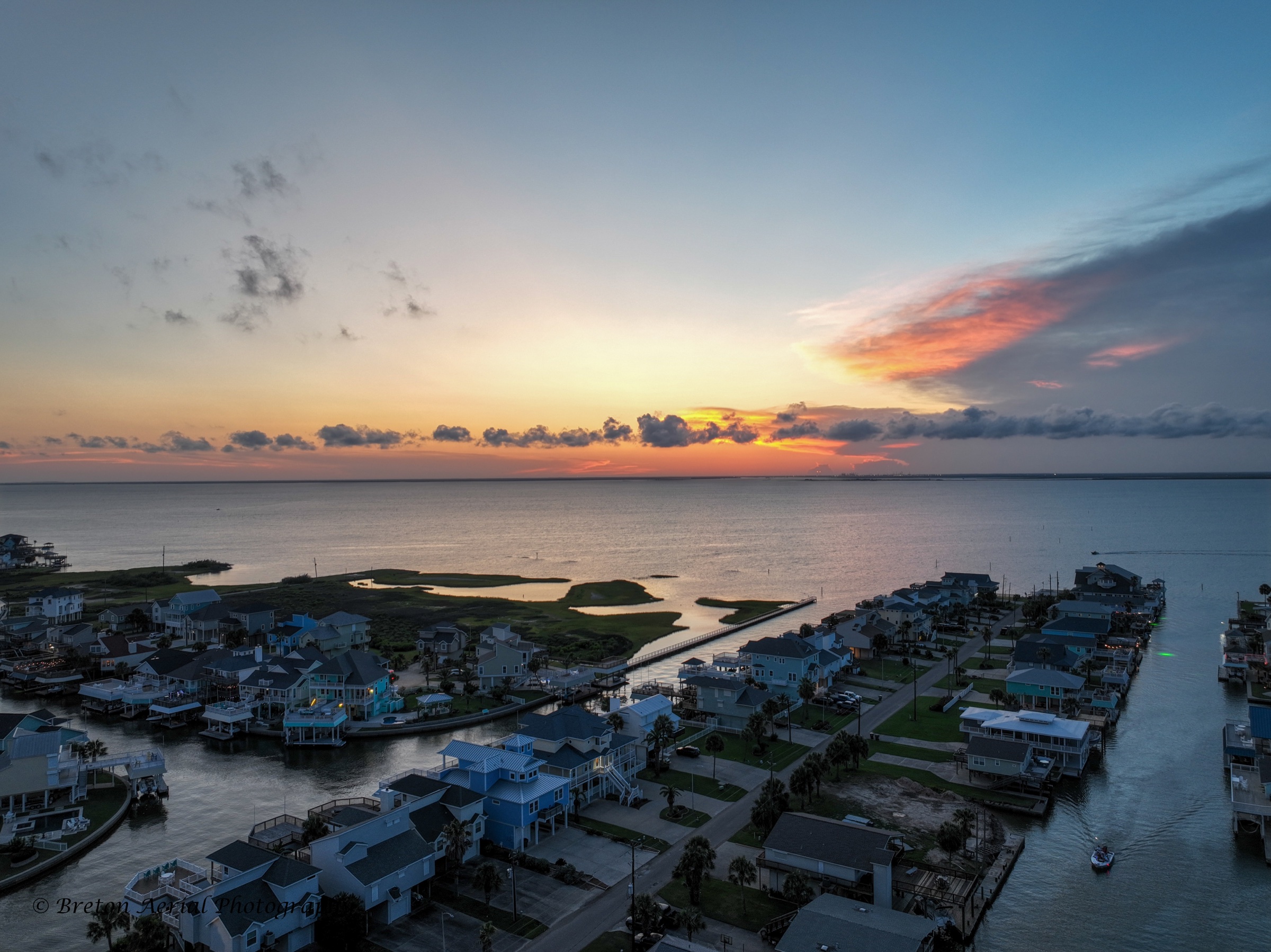 Galveston canals and homes beneath a colorful sunrise
